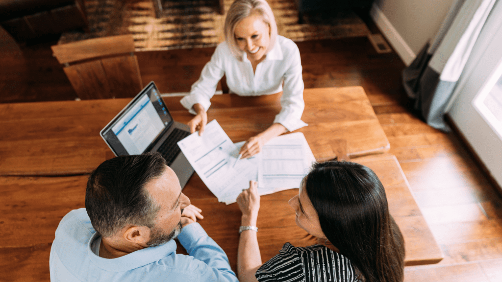 a man and woman sitting down at the table of their home with an accountant