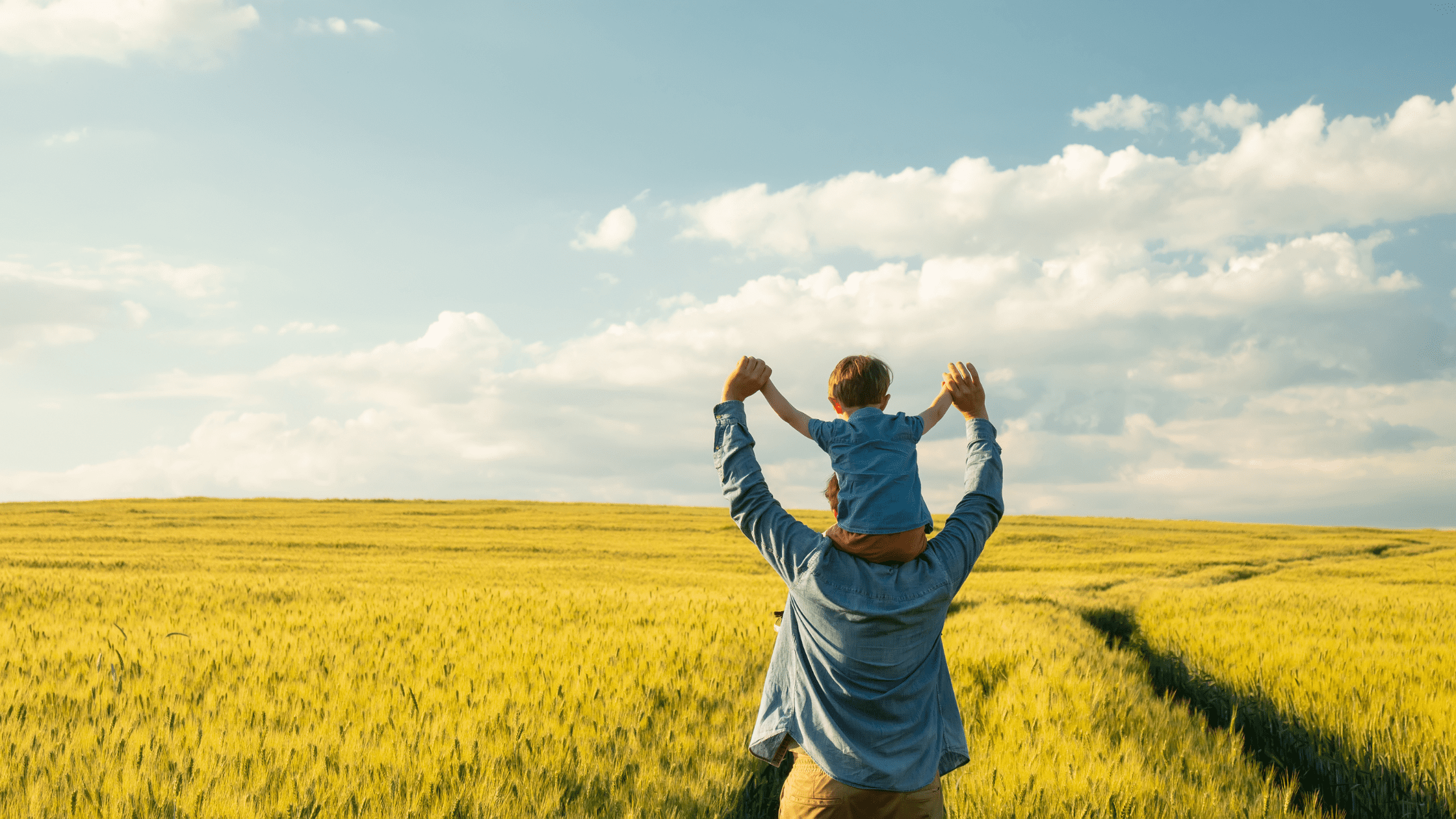 Father with son on his shoulders standing in a grass field